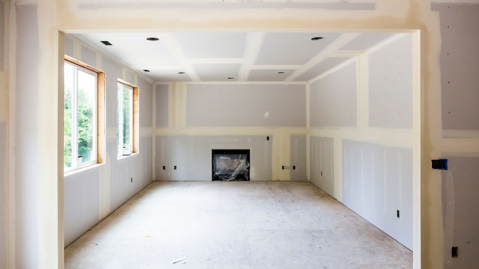 Unfinished room with drywall, windows, and fireplace during home renovation
